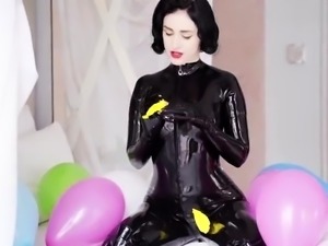 Femdom milf in latex bodysuit plays with balloons on the bed